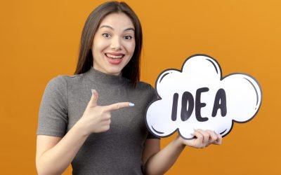 joyful young pretty woman holding and pointing at idea bubble isolated on orange background